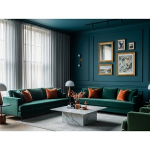 A moody contemporary living room painted in deep teal blue, featuring a plush emerald green velvet sofa and copper-orange throw pillows. Gold-framed art and a marble coffee table add elegance to the richly colored space.